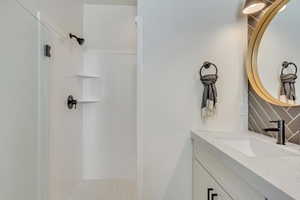 Bathroom featuring decorative backsplash, a shower, and vanity