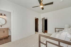 Carpeted bedroom featuring ensuite bathroom and ceiling fan