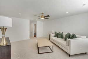 Living room with ceiling fan, a textured ceiling, and light carpet