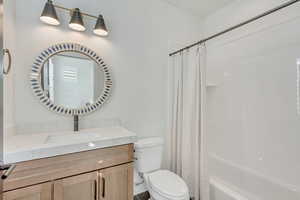 Full bathroom with shower / bathtub combination with curtain, vanity, and toilet