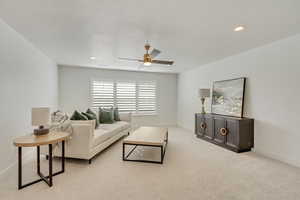 Living room featuring ceiling fan, light colored carpet, and a textured ceiling