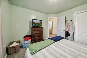 Bedroom with light colored carpet and a textured ceiling