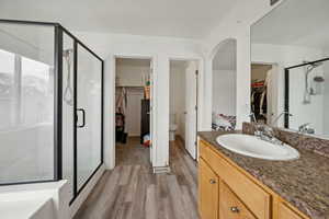 Bathroom with hardwood / wood-style floors, vanity, and a shower with shower door