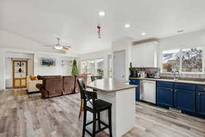 Kitchen with dishwasher, white cabinets, blue cabinetry, a kitchen island, and a kitchen bar