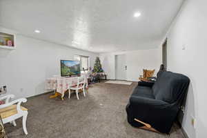 Carpeted living room featuring a textured ceiling