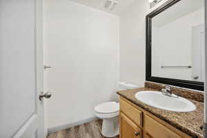 Bathroom featuring hardwood / wood-style floors, vanity, and toilet