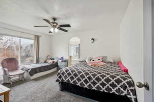 Bedroom with carpet, ceiling fan, and a textured ceiling