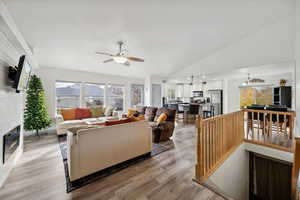 Living room with ceiling fan, light wood-type flooring, and lofted ceiling