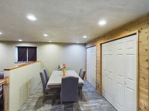 Dining space with wood walls, dark hardwood / wood-style flooring, and a textured ceiling