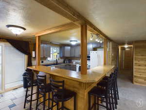 Kitchen featuring a textured ceiling, white appliances, light colored carpet, and sink