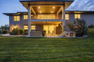 Back house at dusk with yard, and 2 story windows