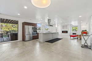 Kitchen with appliances with stainless steel finishes, a kitchen island with sink, and a healthy amount of sunlight