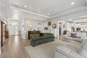 Living room with a raised ceiling and light wood-type flooring