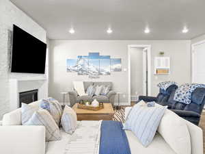 Living room with a stone fireplace and hardwood / wood-style flooring