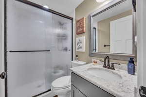 Bathroom with a textured ceiling, vanity, toilet, and walk in shower