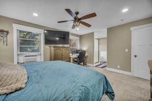 Carpeted bedroom with ceiling fan, cooling unit, and ensuite bathroom