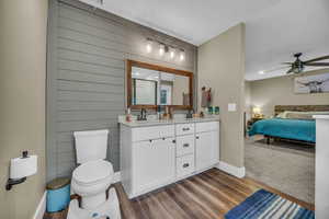 Bathroom featuring vanity, ceiling fan, hardwood / wood-style flooring, toilet, and wood walls