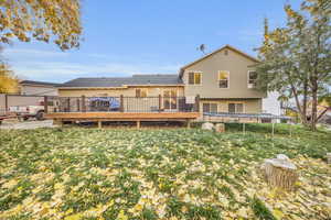 Rear view of house with a deck, a trampoline, and a yard