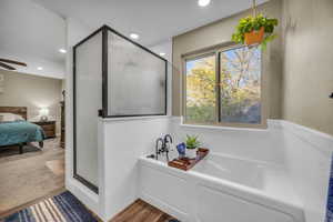 Bathroom with shower with separate bathtub, hardwood / wood-style flooring, and ceiling fan