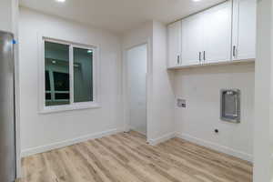 Laundry room featuring hookup for an electric dryer, light hardwood / wood-style floors, cabinets, and washer hookup