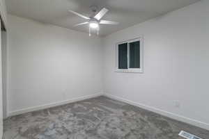 Carpeted spare room featuring ceiling fan