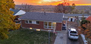 Exterior space featuring new vinyl windows, freshly installed plywood decking, 30 year architectural shingles, with a green lawn, amazing views of the sunset, and a storage unit