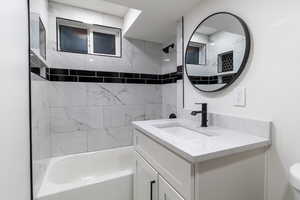 Basement Full Bathroom with vanity and tiled shower / bath, and tiled niche