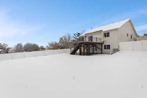 Snow covered back of property with a beautiful wooden deck