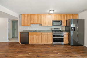 INCLUDED Refridgerator Kitchen featuring appliances with stainless steel finishes, a textured ceiling, sink, and dark hardwood / wood-style flooring