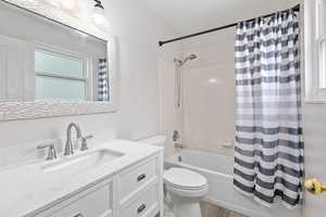 Full bathroom featuring toilet, vanity, shower / bath combo with shower curtain, and hardwood / wood-style flooring