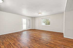 Empty room featuring dark wood-type flooring and a textured ceiling