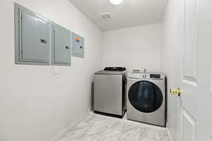 Downstairs Washroom featuring electric panel, a textured ceiling, and INCLUDED washer and dryer