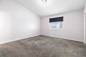 Spare room featuring vaulted ceiling and carpet floors