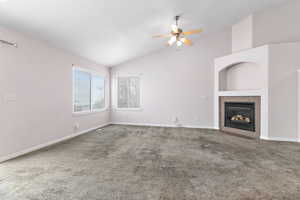 Living room featuring carpet flooring, lofted ceiling, ceiling fan, and a tile fireplace