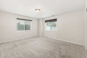 Empty room with a textured ceiling and light carpet