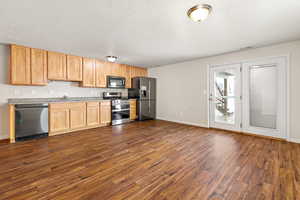 ADU Kitchen and walk-out featuring dark wood-type flooring, a textured ceiling, sink, and INCLUDED appliances with stainless steel finishes