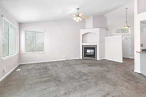 living room featuring dark colored carpet, a tiled fireplace, ceiling fan, and high vaulted ceiling