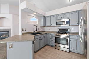 Kitchen with INCLUDED stainless steel appliances, gray cabinetry, sink, and kitchen peninsula