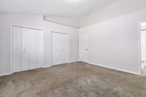 Bedroom with carpet, vaulted ceiling, two closets, and ensuite bath