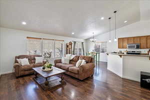 Living area featuring a wealth of natural light, recessed lighting, dark wood-type flooring, and vaulted ceiling