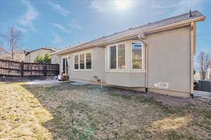 Back of property with entry steps, a yard, stucco siding, and fence