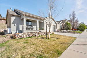 Ranch-style house featuring central AC unit, an attached garage, covered porch, stucco siding, and driveway