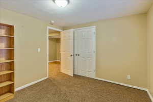 Unfurnished bedroom with carpet flooring, a textured ceiling, and a closet