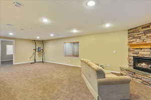 Living room with carpet flooring, a fireplace, baseboards, and recessed lighting