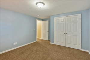 Unfurnished bedroom featuring carpet, a textured ceiling, and a closet