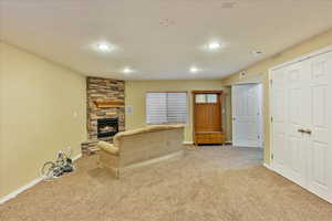 Unfurnished living room with a stone fireplace, light colored carpet, and a textured ceiling