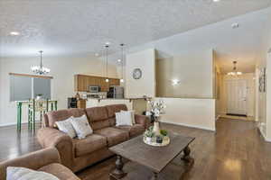 Living room featuring a textured ceiling, dark hardwood / wood-style floors, an inviting chandelier, and lofted ceiling