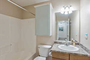Bathroom featuring a chandelier, vanity, shower / washtub combination, and toilet