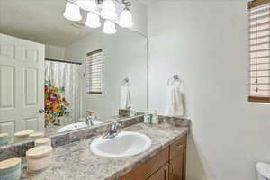 Bathroom with curtained shower, a chandelier, and vanity