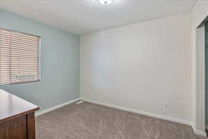 Carpeted spare room featuring baseboards